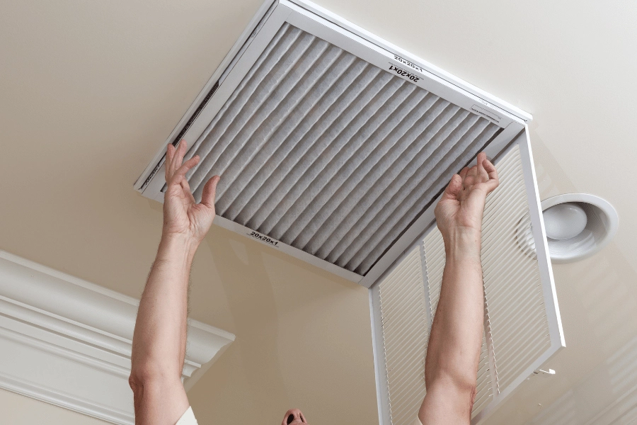 homeowner changing HVAC filter on ceiling